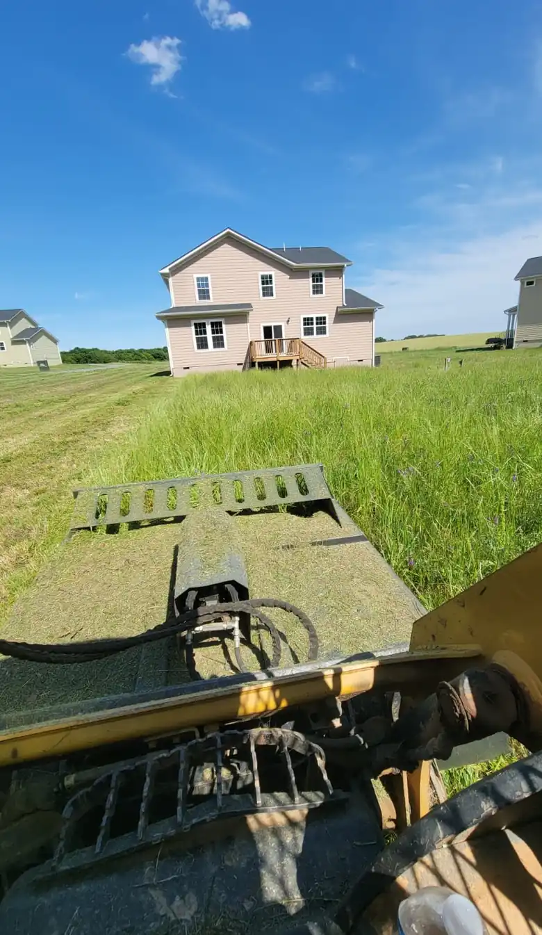 Bush hogging an overgrown field beside a home in Charlotte, NC