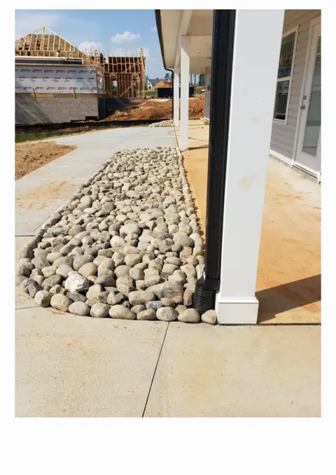 Cama de drenaje con piedra de río instalada junto a una casa en Charlotte, NC