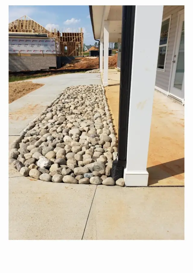 River rock drainage bed at a downspout corner in Charlotte, NC