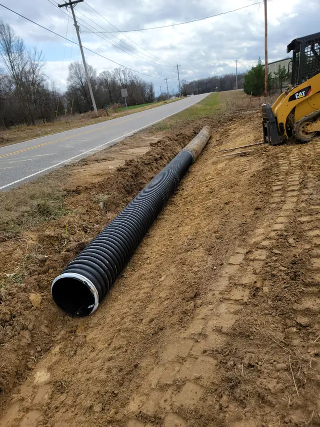 Skid steer working roadside near a drainage pipe install in Charlotte, NC